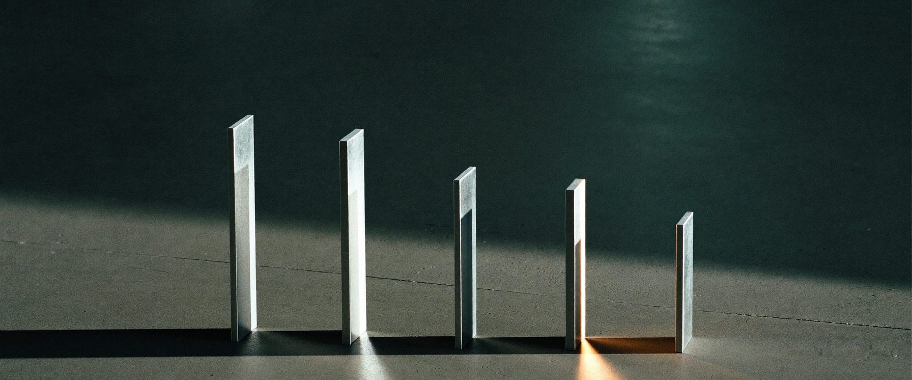 Five upright slabs of differing height on a concrete floor, one lit from the side.
